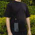 A black phone lanyard securely holding a smartphone, worn around the neck over a black shirt.