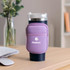 A drink bottle pouch in lilac, designed for a dark blue Stanley bottle, featuring a logo on the front.