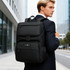 A black business laptop backpack with various compartments, carried by a man in a suit outside a modern building.