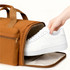 A foldable travel duffle bag in brown, with a hand placing a white sneaker inside. It features a zippered compartment.