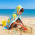 A kids' hooded towel surf shawl in blue with palm tree and starfish designs, worn by a child on the beach.