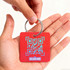 A red custom shape plastic card key tag held in a hand, featuring a QR code and a metal keyring.
