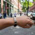 A metal silica bracelet with a sleek design, worn on a wrist, in an urban street setting.