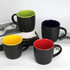 A set of four coffee mugs with black exteriors and coloured interiors in green, blue, yellow, and red.