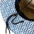 A straw hat with a blue and white geometric pattern and an adjustable chin strap. It features a woven interior.