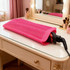A pink heat-resistant silicone mat pouch with textured surface, placed on a vanity table. It has a styling tool resting on it.