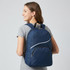 A navy blue backpack with a zippered front pocket and a logo, being worn by a young woman.