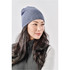 A knit beanie in navy blue, worn by a woman with long dark hair, paired with a grey vest.