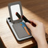 A grey PU magnetic card holder with a mirror is open, displaying a card and two lipsticks on a wooden surface.