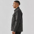 A men's dark grey canvas jacket featuring a Sherpa lining and a chest pocket, side view.