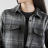 A stylish women's shacket featuring a black and grey Highland plaid pattern with buttoned pockets.