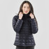 A woman wearing a black puffer jacket with a high collar, standing against a neutral background.