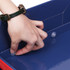 A hand fastens a connector inside a red and blue three-tier counter display unit. The unit features a sleek design.