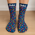 A pair of navy socks decorated with colourful bean-shaped patterns, featuring a logo at the top.