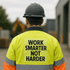 A worker in a high-visibility yellow jacket and hard hat, facing away, on a construction site.