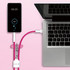 A pink 4-in-1 charging phone lanyard connected to a laptop and a smartphone displaying battery percentage.