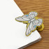 A butterfly-shaped metal clip in pastel colours, holding together the edge of stacked white papers.