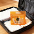 An orange transparent cosmetic pouch filled with toiletries, placed inside a suitcase alongside folded clothes.
