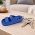 A blue sandal-shaped keyring rests on a wooden table beside a set of keys.