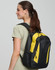 A black and yellow backpack with a logo, worn over one shoulder by a woman with long brown hair.