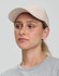 A beige Jacquard Texture 5 Panel Cap worn by a woman, featuring a curved brim and a minimalist design.