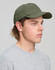 A green cotton twill unstructured cap is displayed on a person with light brown hair, wearing a grey shirt.