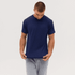 A navy blue T-shirt is held by a person, wearing grey shorts, showcasing its simple design. The image includes a logo.
