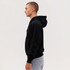 A black zip hoodie is displayed on a model, showcasing a side view against a plain background.