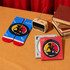 A red and blue pair of socks, a vintage radio, and two CDs in decorative cases on a table with books.