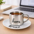 A stainless steel mug with a mirror finish, featuring a black handle and a white saucer beneath it.