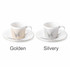A coffee mug set featuring a golden and a silvery mug with corresponding saucers, both with a decorative design.