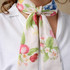 A floral-patterned long scarf in soft hues of pink, green, and blue, tied around a person's neck.