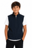 A boy stands wearing a navy blue vest over a white T-shirt, with his hands in his pockets. The vest has branding.