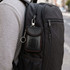 A black carbon fibre Faraday key pouch with red trim attached to a backpack.