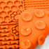 An orange silicone lick mat divided into four sections with various textures, including honeycomb and paw prints.