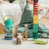 A drink bottle in turquoise and blue features playful graphics, placed next to a child playing with colourful blocks and toys.