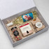 A drink bottle of white wine, a jar of Christmas rock, a box of Christmas snacks, and a pack of caramel fudge in a gift box.