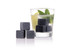 A drink glass with mint and lime contains grey gin stones beside it, set against a white background.