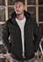 A black unisex hooded puffer jacket with a zip front, worn by a model in a construction setting.