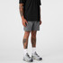 Active shorts in grey, designed for sports, paired with a black top and grey athletic shoes. Features a logo.