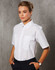 A white short sleeve button-up shirt with two chest pockets, modelled by a woman against a textured background.
