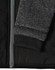 A black quilted body jacket with a heather grey sleeve and ribbed cuffs, featuring a zip closure.