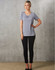 A grey short-sleeve knit top with pleats, paired with black fitted pants, worn by a model against a textured background.