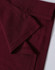 A close-up of a maroon polo shirt showing folded fabric and stitching details. It features a logo on the collar.