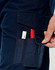 A pair of navy work pants with pockets, featuring red stitching and a hand reaching into a side pocket.