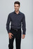 A long-sleeve button-up shirt in dark grey, worn by a smiling male model, featuring a subtle logo.