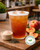 Peach oolong iced tea in a clear takeaway cup, amber coloured fruit tea served over ice in a café setting