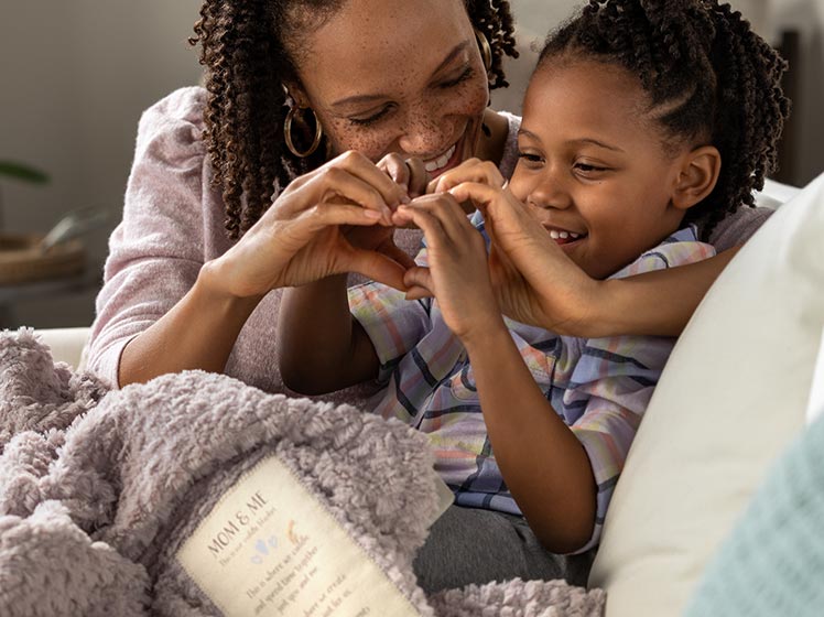 md-cuddle-blanket.jpg Mom and child cuddled under a soft pink blanket