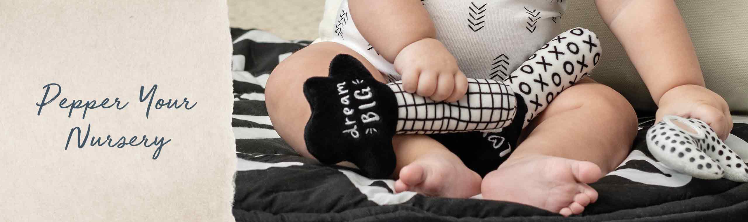 Pepper your Nursery! a baby wearing black and white socks, clothes and playing with a blank and white toy