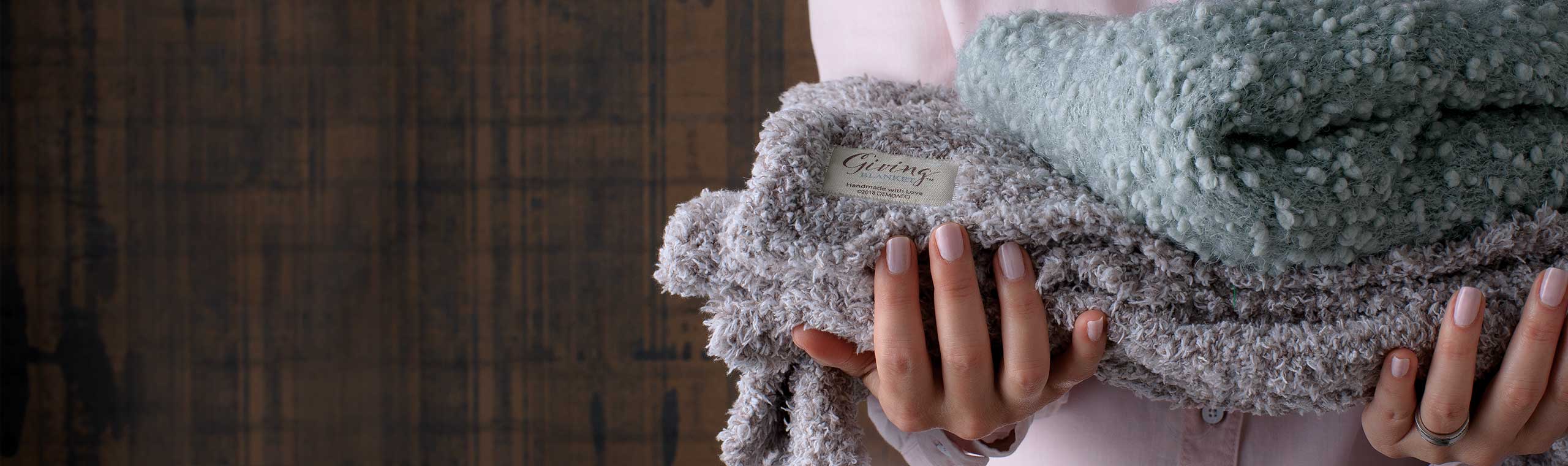 A woman holding a stack of giving blankets